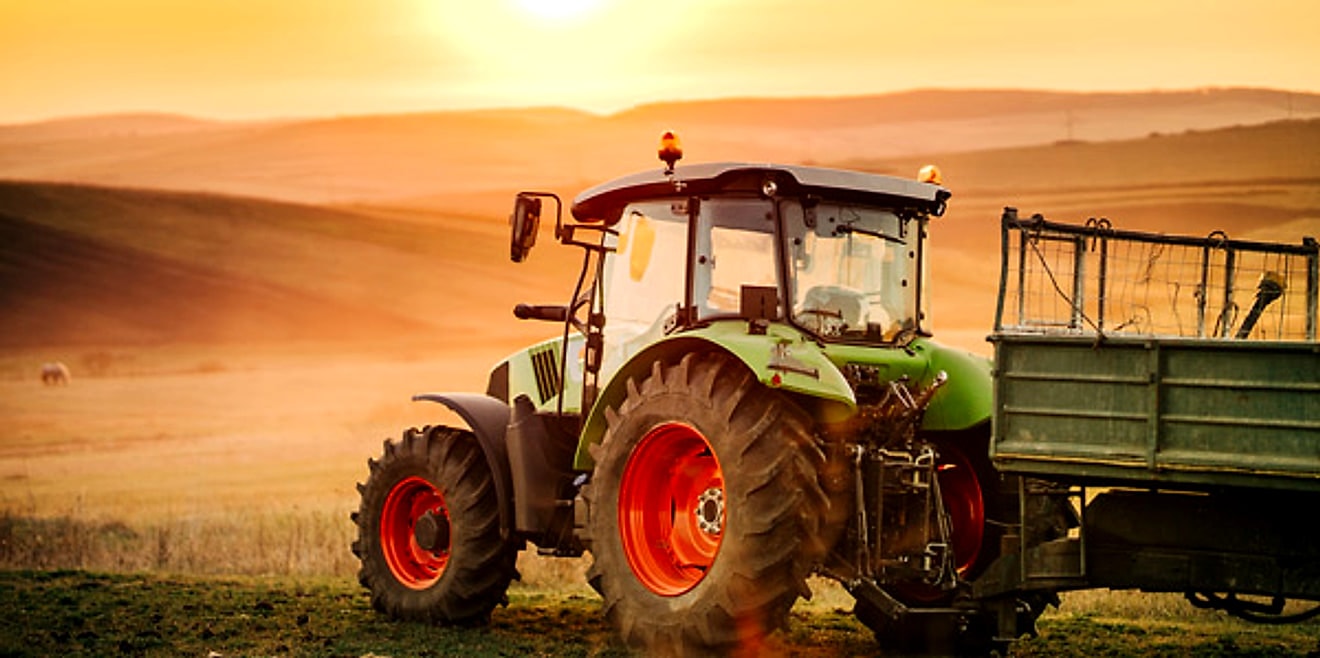 A tractor working golden fields at dusk